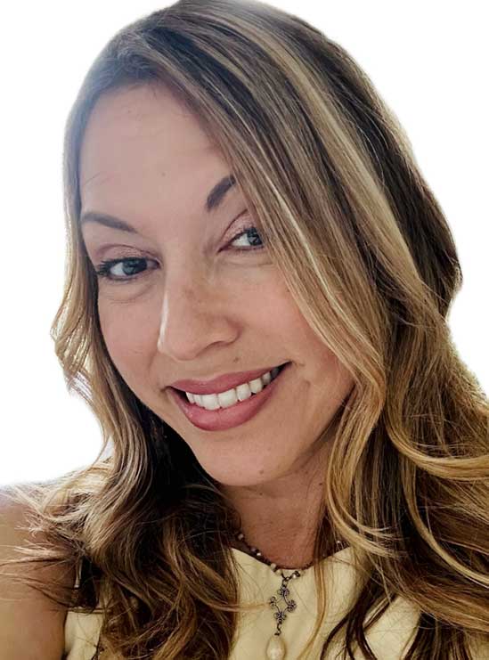 Smiling woman with long wavy light brown hair, wearing a light top and a necklace, in front of a white background.